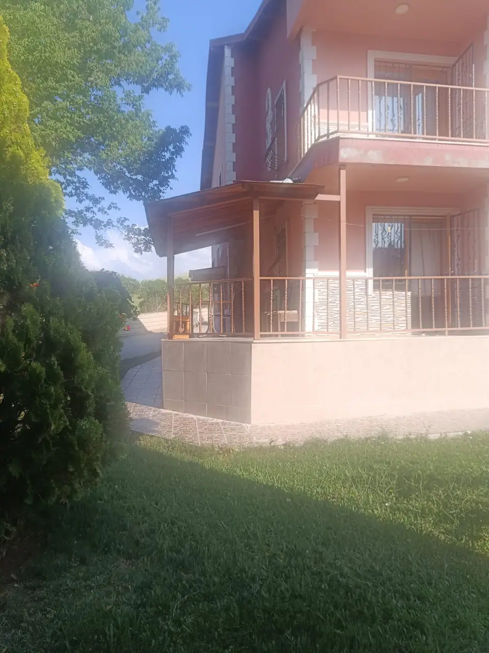Çimenlik bahçenin ucunda balkonlu villa ve ahşap pergolalı teras