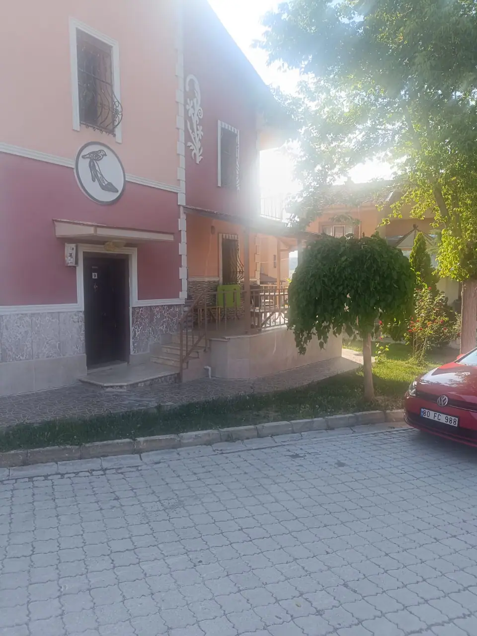 Amblemli ön cephe, giriş kapısı ve parke taşı döşeli sokak