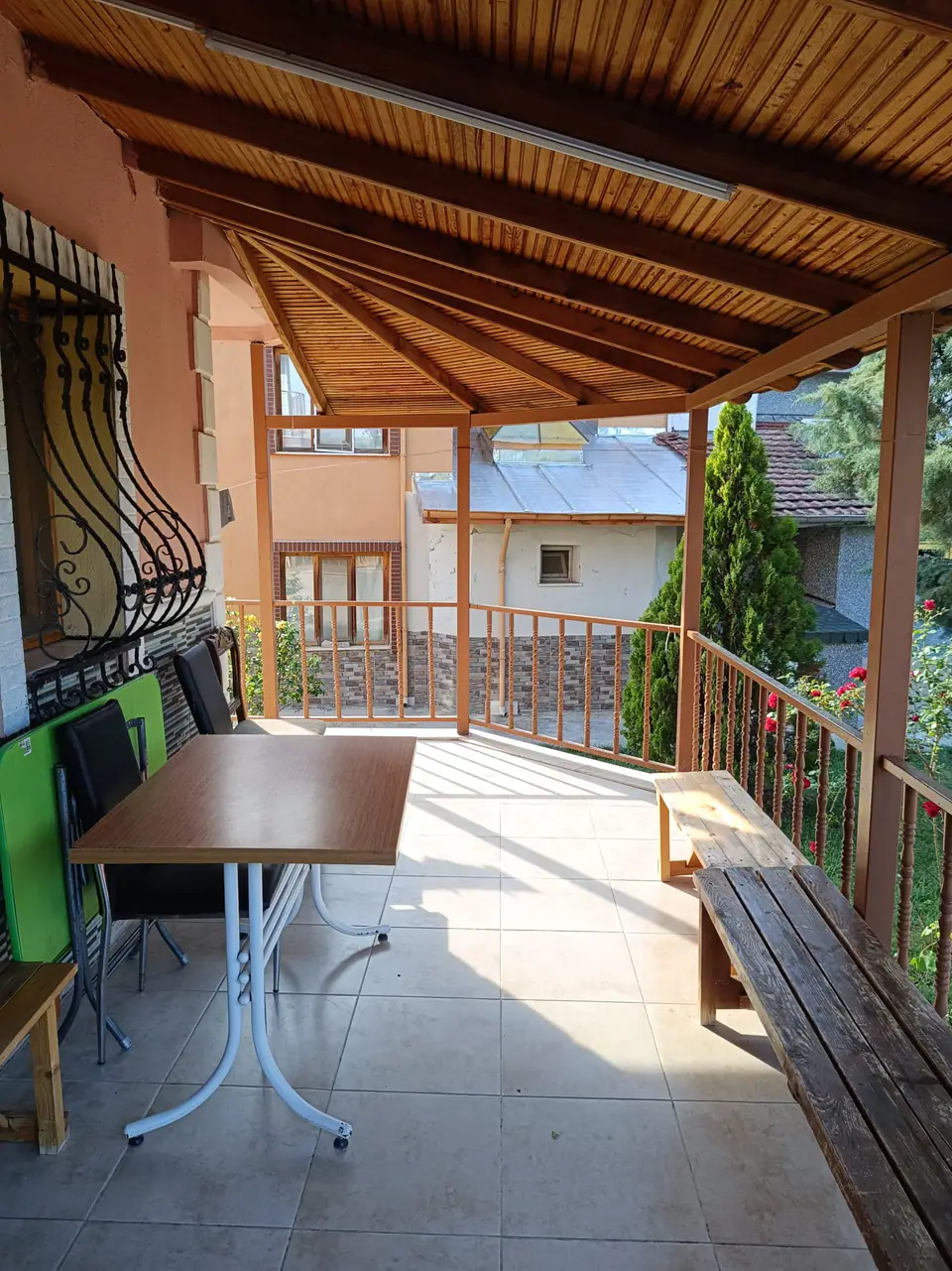 Ahşap tavanlı kapalı terasta masa, sandalyeler ve ferforje pencere