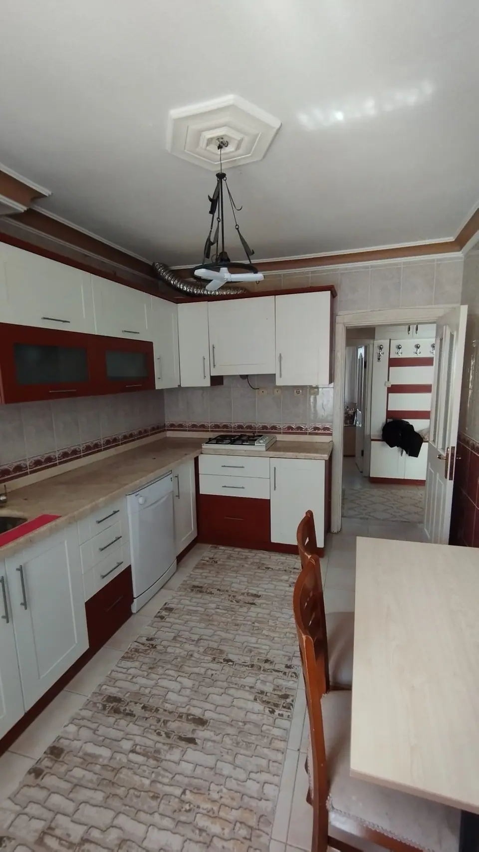 Kırmızı-beyaz dolaplı, L tezgâhlı mutfak ve yemek masası
