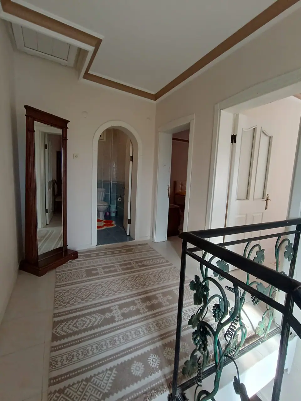 Kemerli kapılı üst kat sahanlığı, boy aynası, kilim yolluk ve asma motifli ferforje