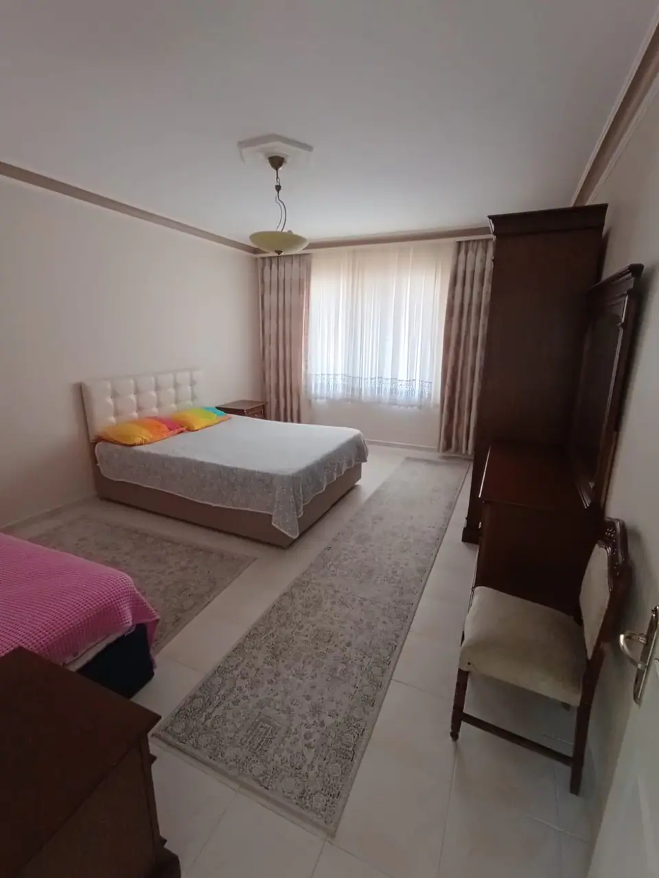 Kapitone başlıklı çift kişilik yatak, tek kişilik yatak ve koyu ahşap dolaplar